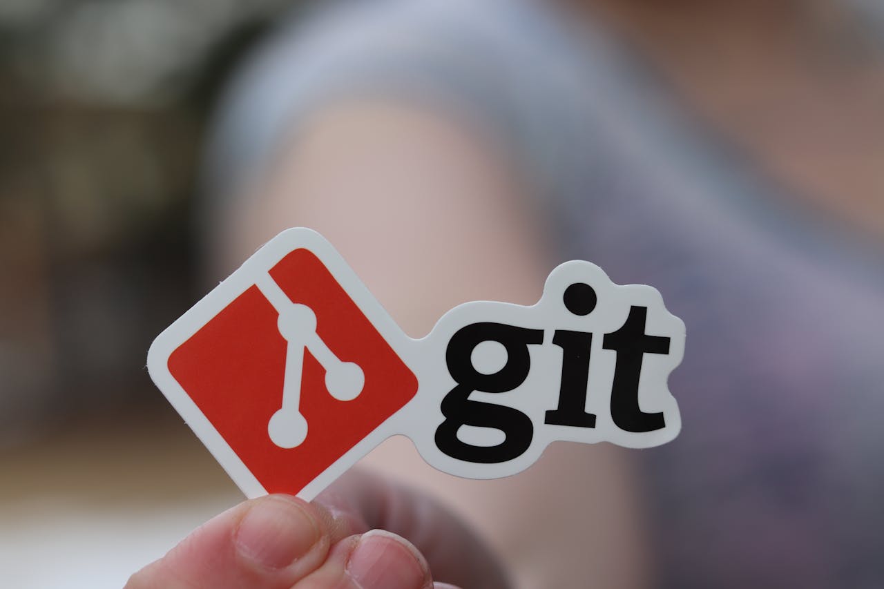 The Art of Drawing Readers In: Your attractive post title goes here Close-up of a person holding a Git sticker, emphasizing software development.